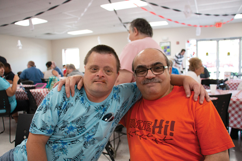 two men smiling with arms around each other's shoulders