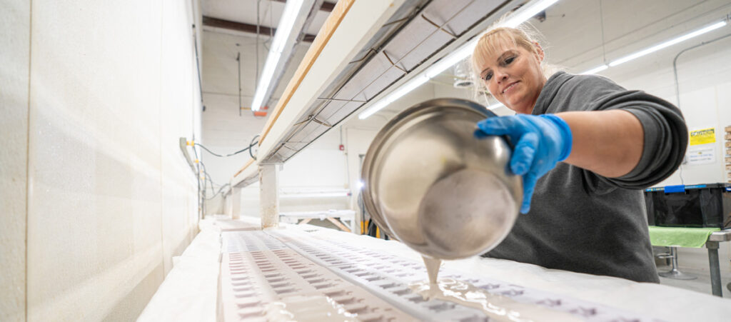 female worker pouring liquid clay into molds. Goodwill manufactures and packages products for companies like Tetra.
