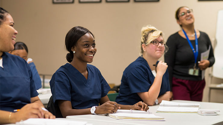 3 nursing students sitting in a classroom, smiling