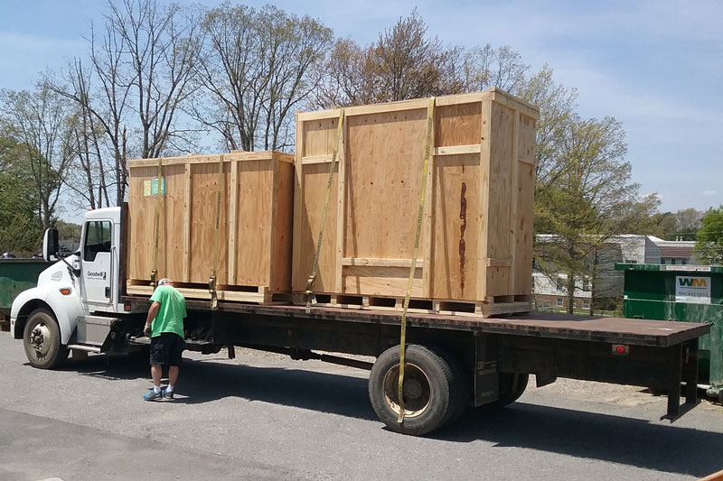 two very large wood crates tied onto bed of a semi-truck trailer