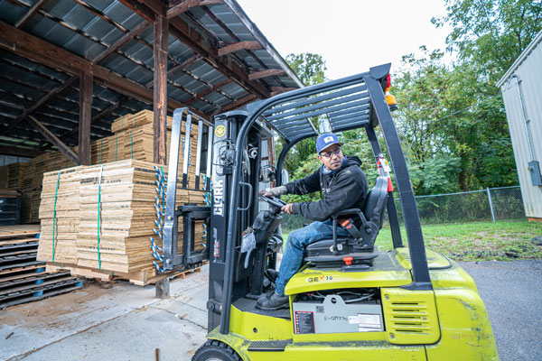 goodwill team member operates a forklift to pick up a stack of wood outrigger pads
