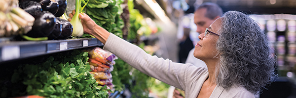 middle-aged Black woman shopping in produce section at a market
