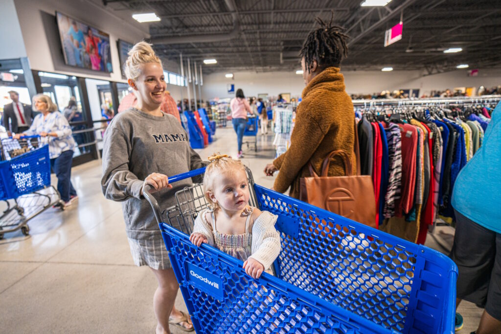 A woman pushing a shopping cart with a child inside